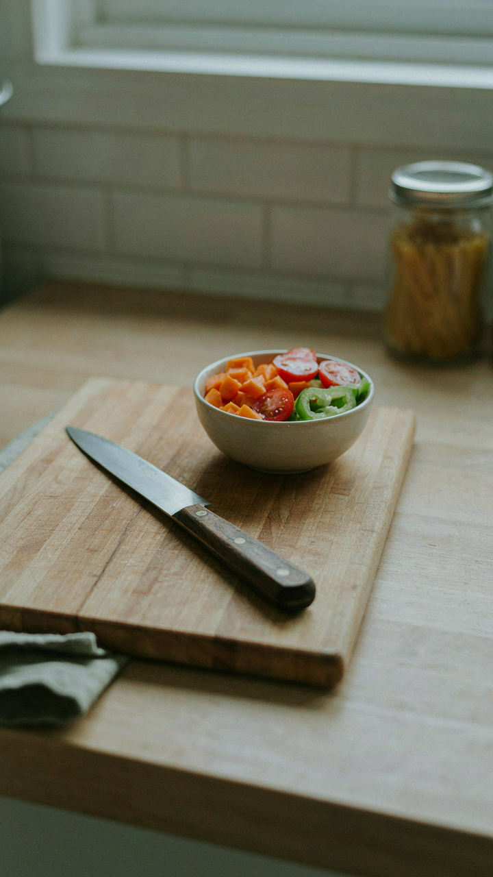 A neat chopping station in a tiny kitchen with a cutting board and knife.
