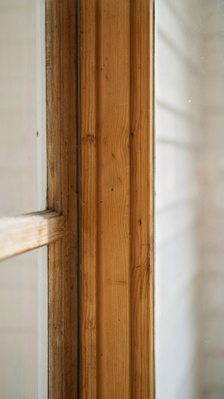 A close-up of a new wooden window frame perfectly matching existing trim.