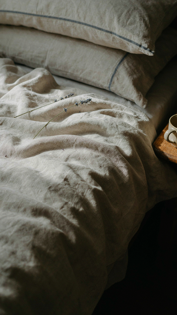Close-up of rumpled linen bedding with natural wrinkles in an english cottage bedroom.
