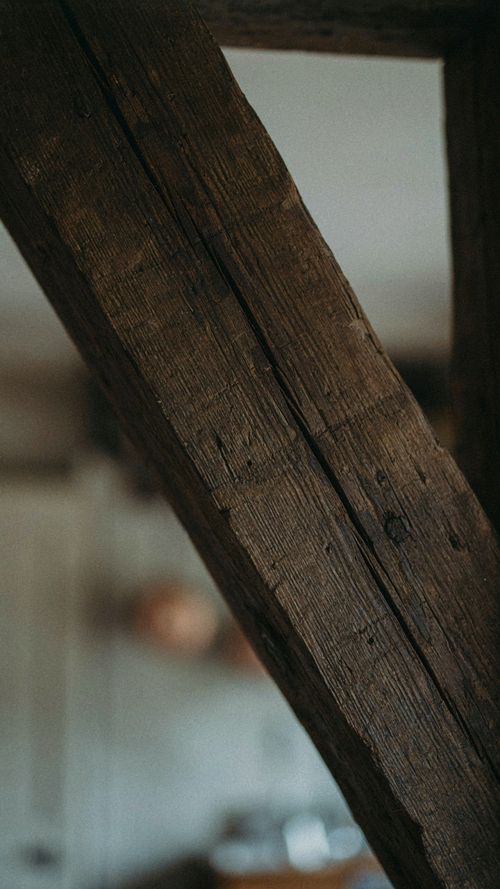 An old wooden beam in a rustic cottage kitchen, darkened with age and humidity.