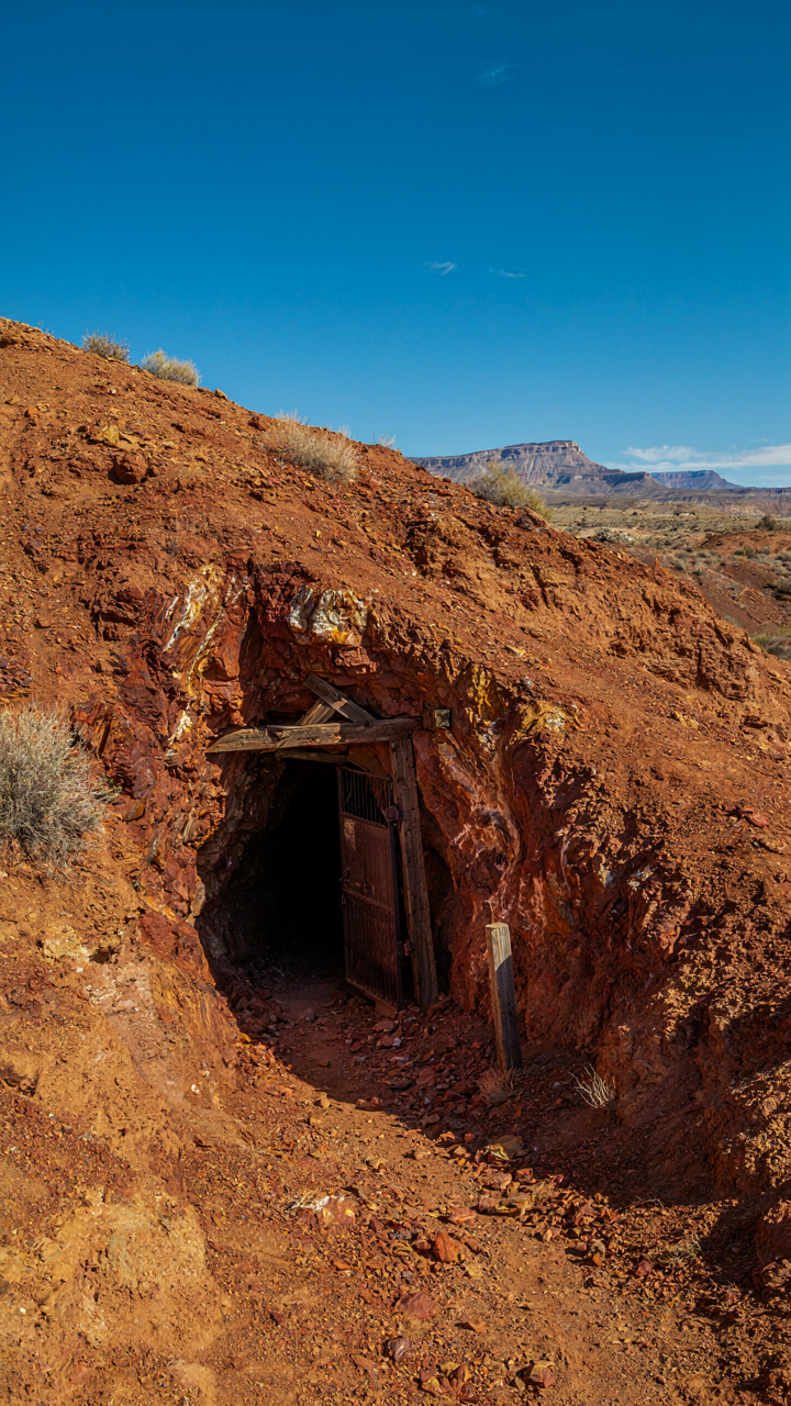 Entrance to an old copper mine with deep red soil and rocks.