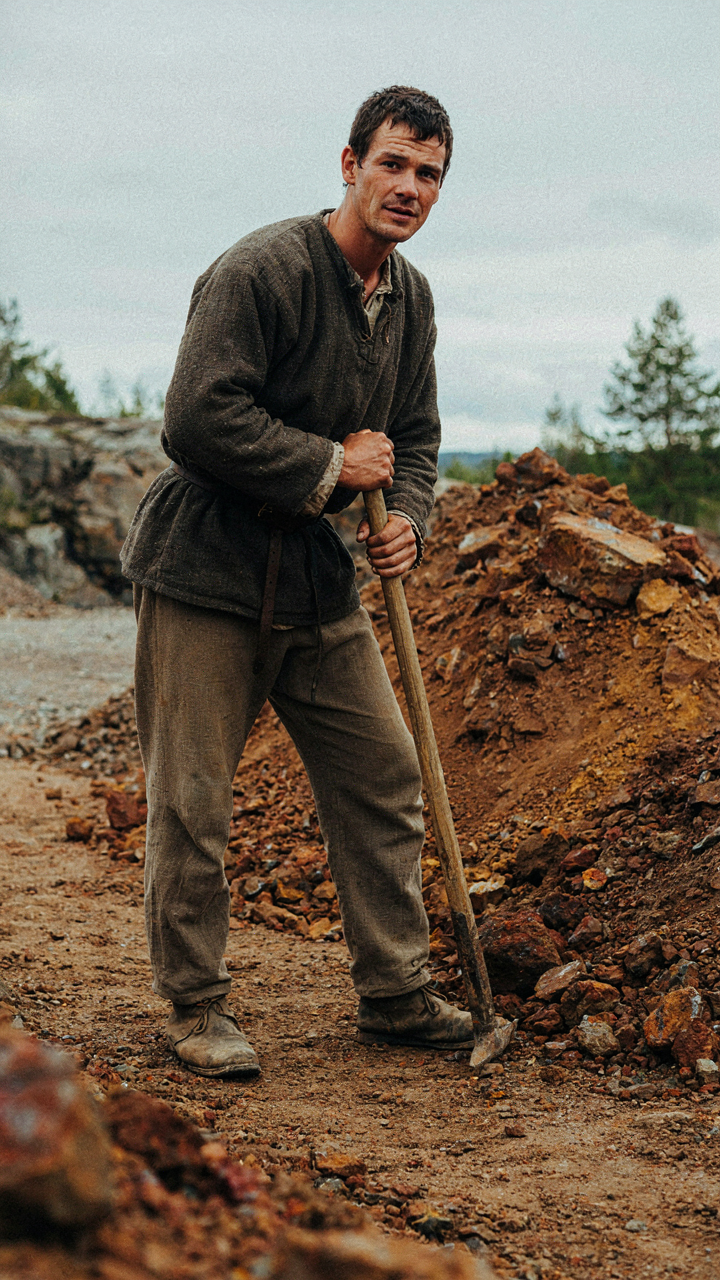 A 17th-century miner stands near mining waste, representing the origin of Falu Red.