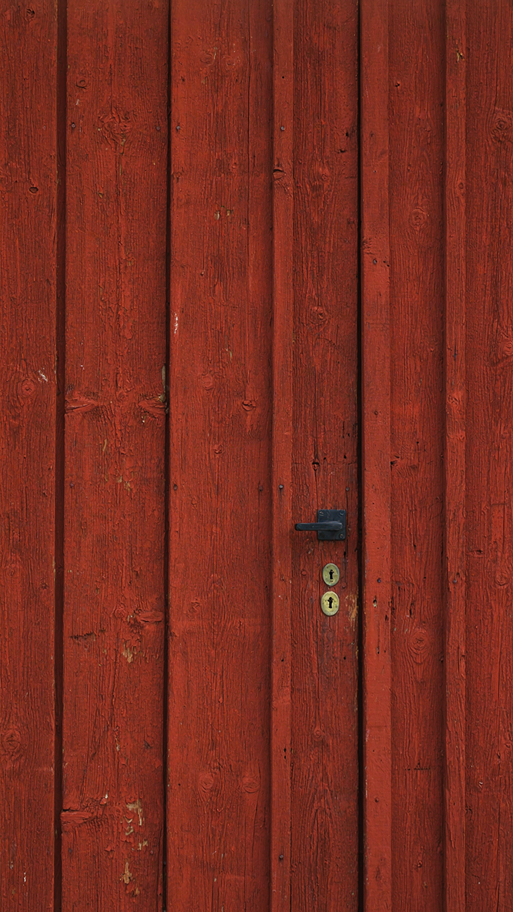 A weathered Falu red painted wooden barn wall shows deep red texture.