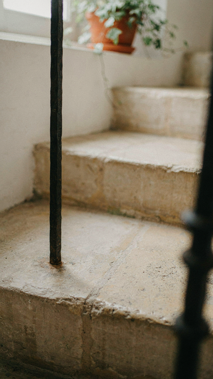 A hand-forged iron baluster fitted into an uneven stone step.