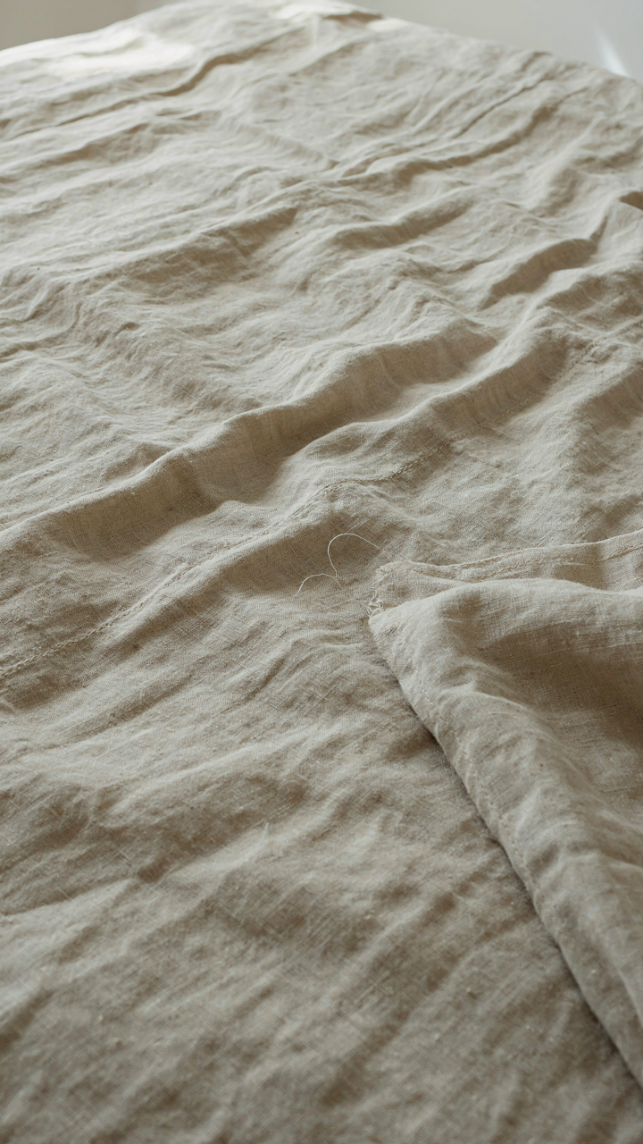 A close-up of a well-worn linen duvet cover on a scandinavian cottage bed.