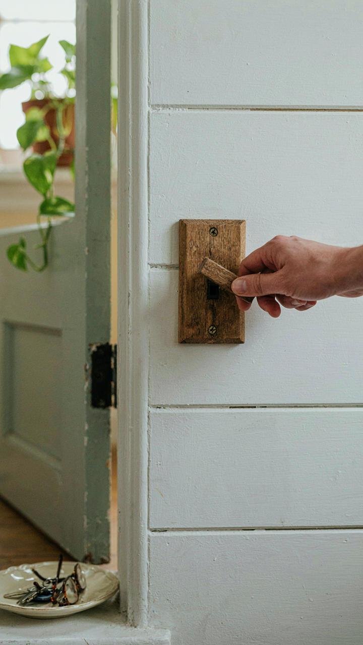 A hand turns on a light switch in a cottage home office.