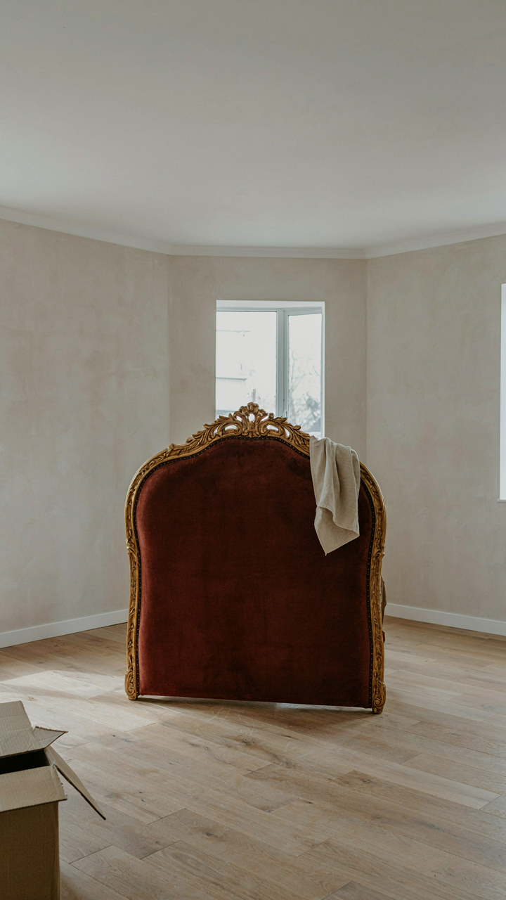 An ornate velvet headboard in a minimalist room, looking out of place.