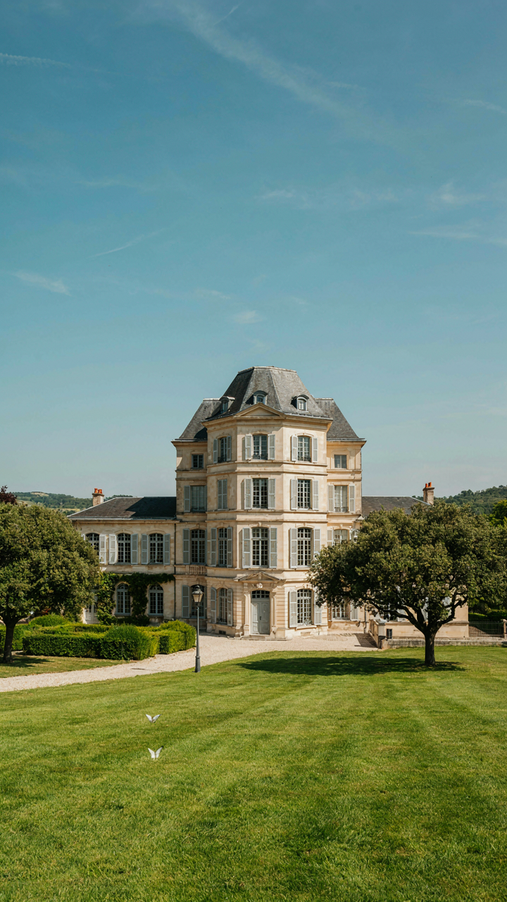 A beautiful, scaled-down French villa stands elegantly on a green lawn.