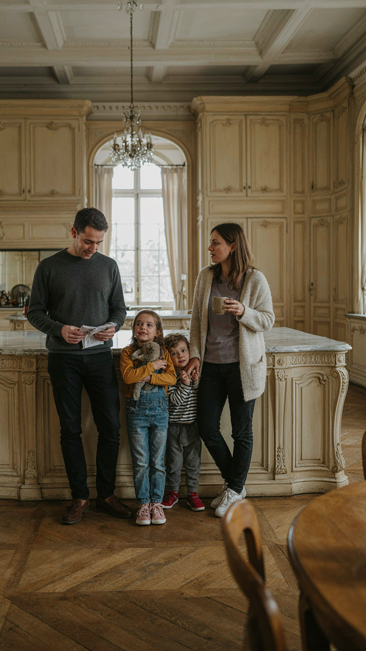 A small family looks out of place in a vast, ornate chateau kitchen.
