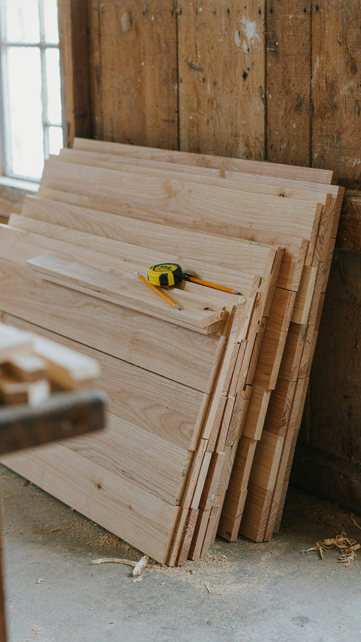 Unfinished shiplap boards leaning against a wall in a workshop.