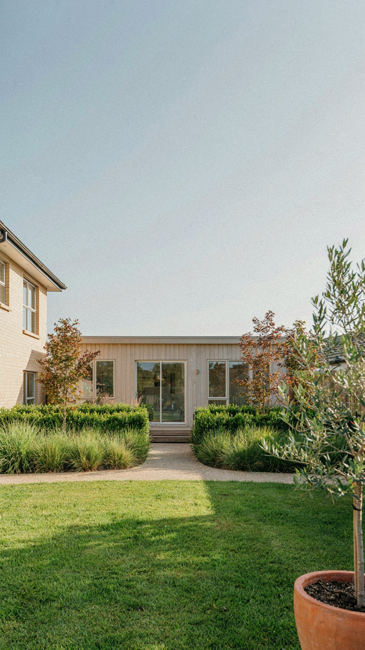 A granny flat cottage sits a good distance from a main house with green landscaping.