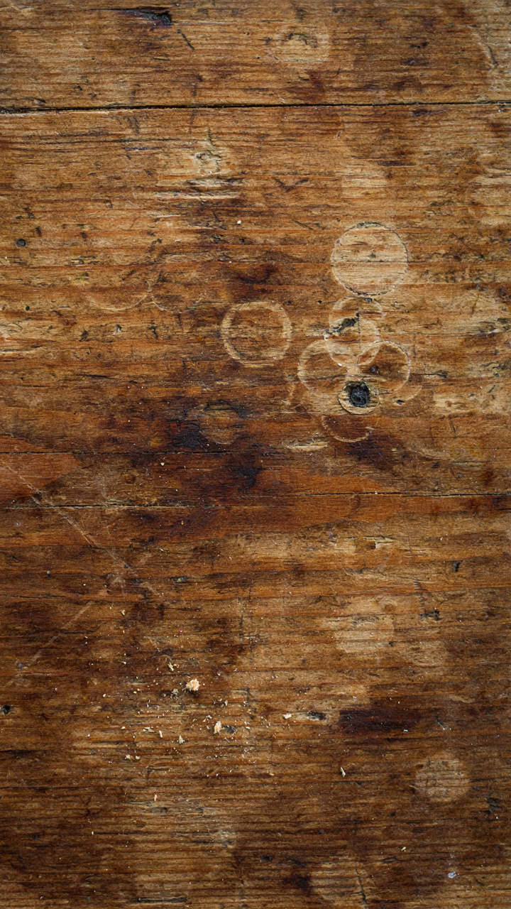 Close-up of an old, well-worn wooden farmhouse table showing its authentic patina.