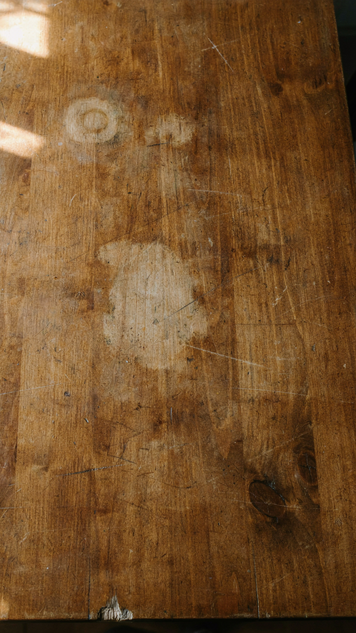 Close-up of an old wooden farmhouse table with authentic wear marks.