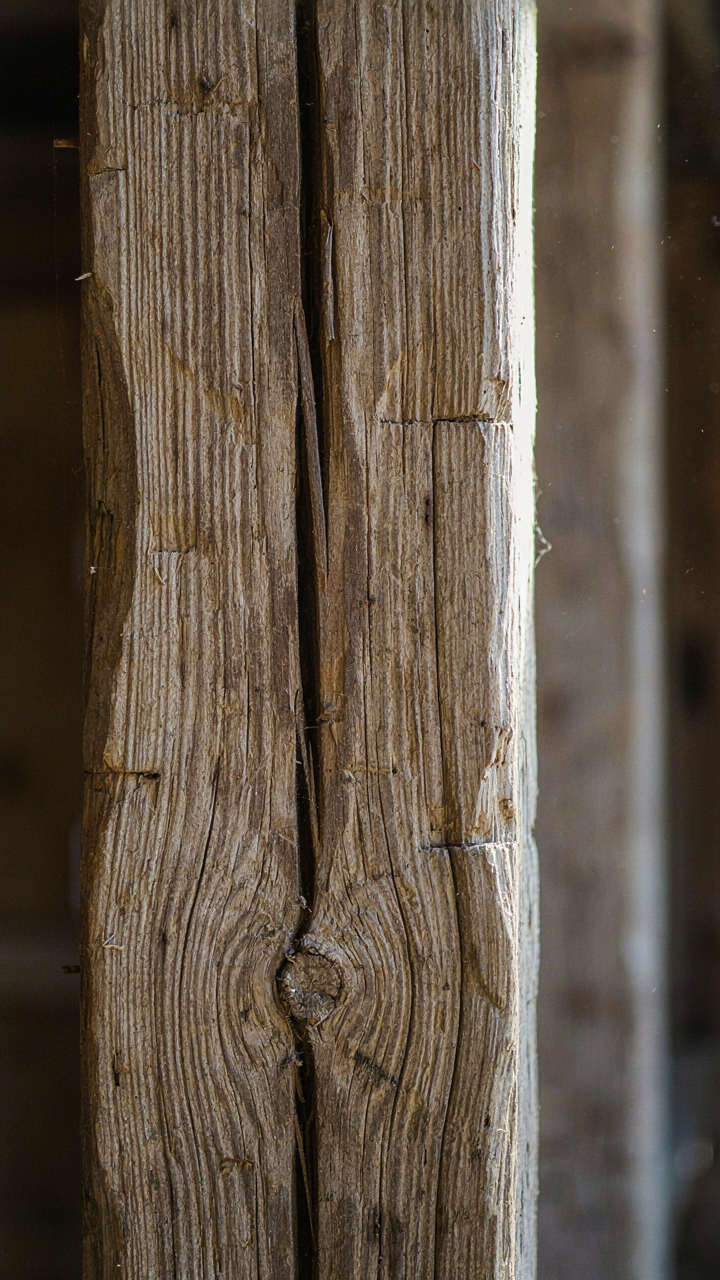 A close-up of a truly weathered wooden beam with deep cracks and varied color.