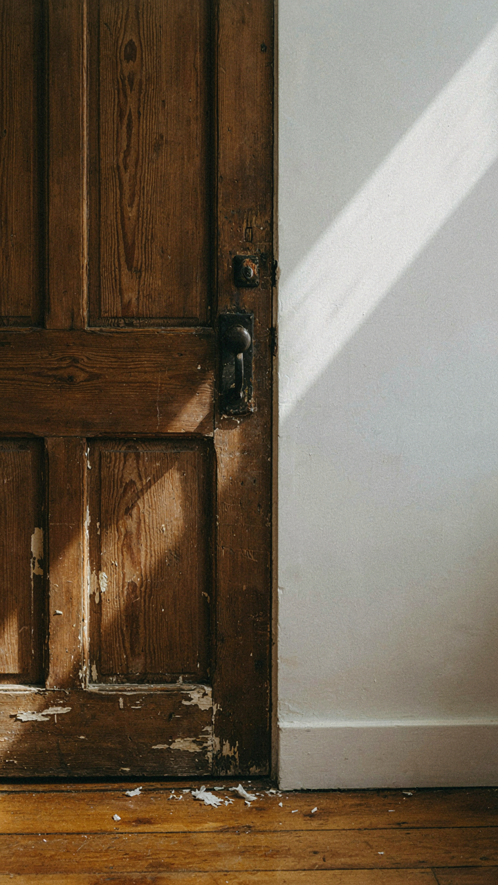 A rustic, chipped wooden door next to a pristine modern white wall.
