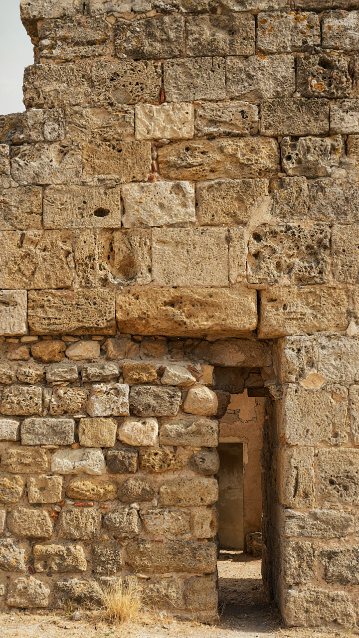 A close-up view of a very thick stone wall, showing its rugged surface.