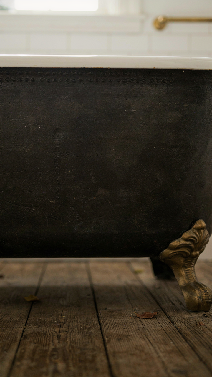 Underside of an antique cast iron clawfoot tub with visible manufacturer marks.