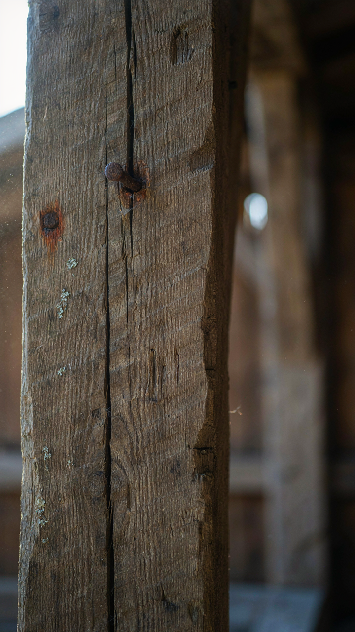 A close-up of a weathered, hand-hewn timber beam showing its genuine age.