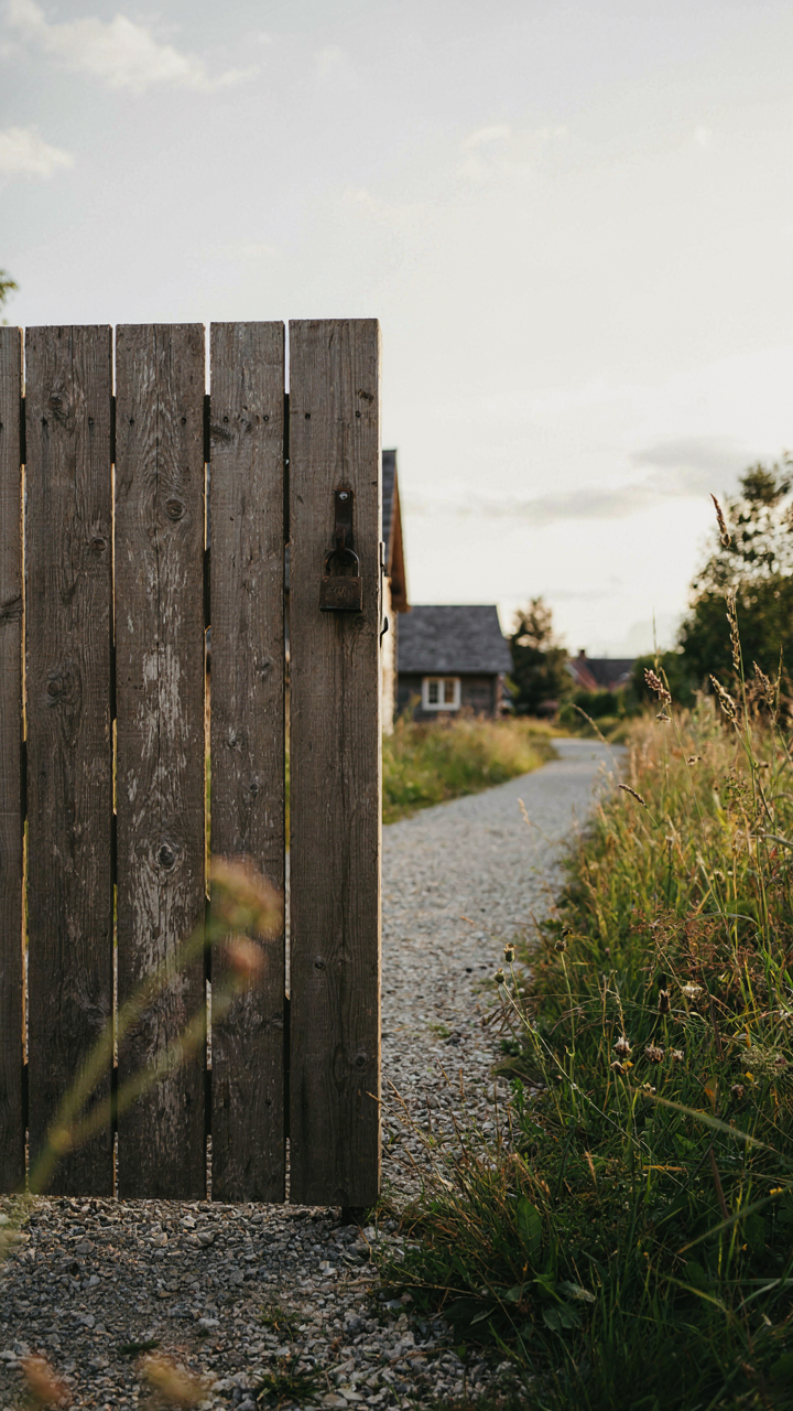 A rustic wooden gate clearly marks the path to a guest cabin, separating it from the main house.
