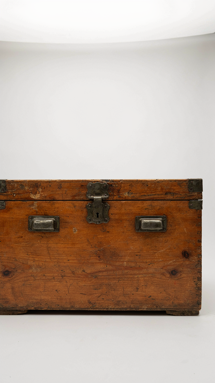 A new, distressed wooden chest with shiny hardware in a clean showroom.