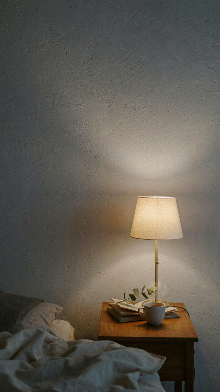 A soft pool of light from a bedside lamp creates a cozy zone in a cottage bedroom.