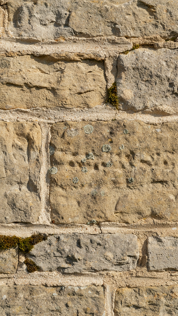 A close-up view of an old stone wall built with lime mortar and moss.