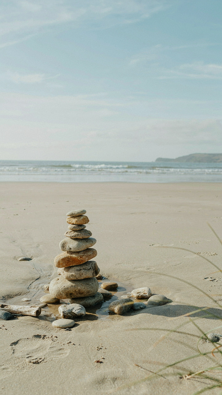 A perfectly balanced rock cairn on a beach, showing equilibrium and lagom.