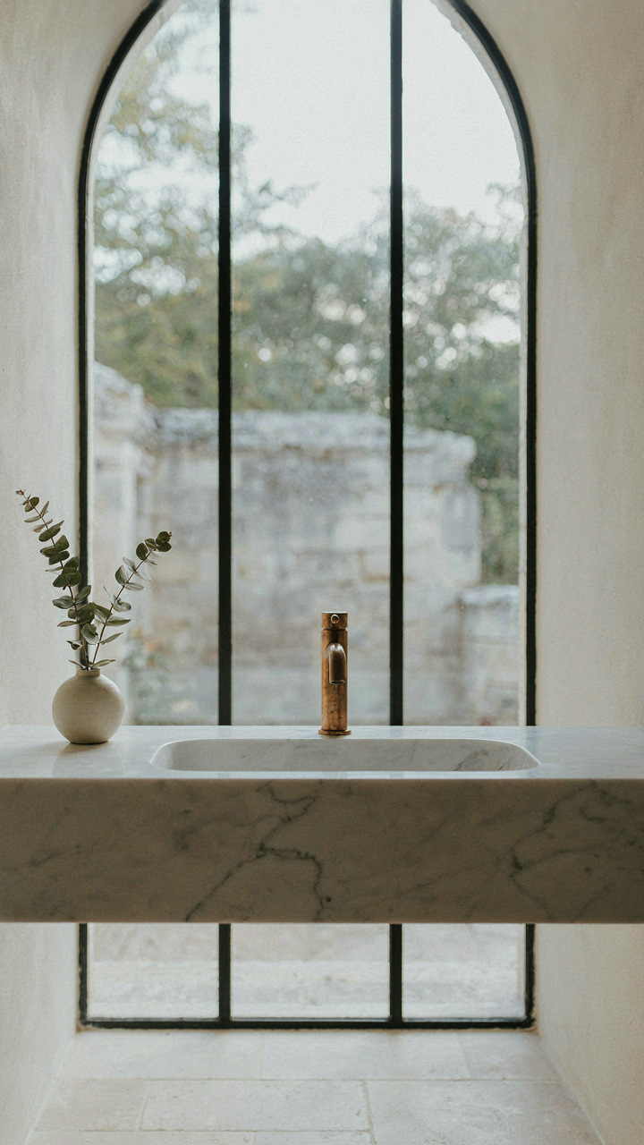 A single Carrara marble countertop and bronze faucet in a chateau style bathroom.