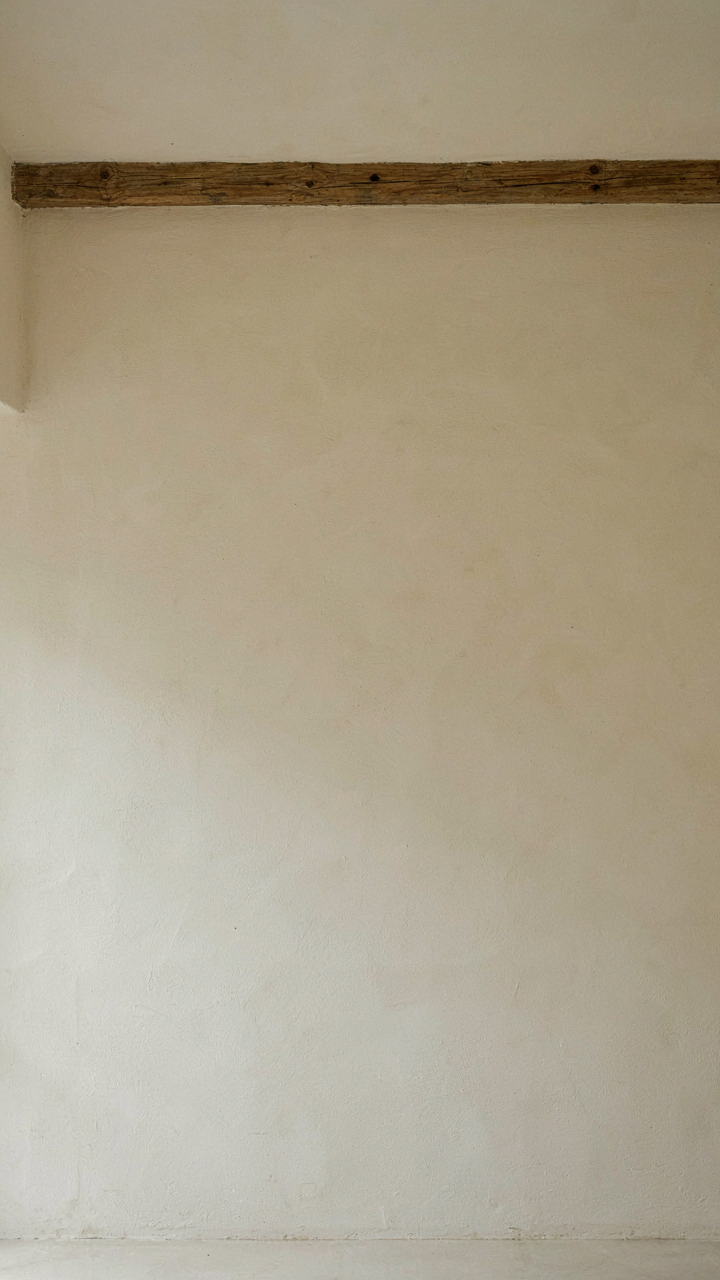 A minimalist modern rustic bedroom wall with a single wooden beam and empty space.