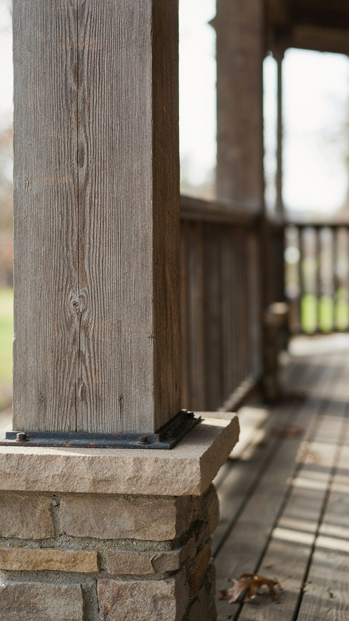 Weathered but well-maintained wood tapered column on a craftsman porch next to a stone foundation.