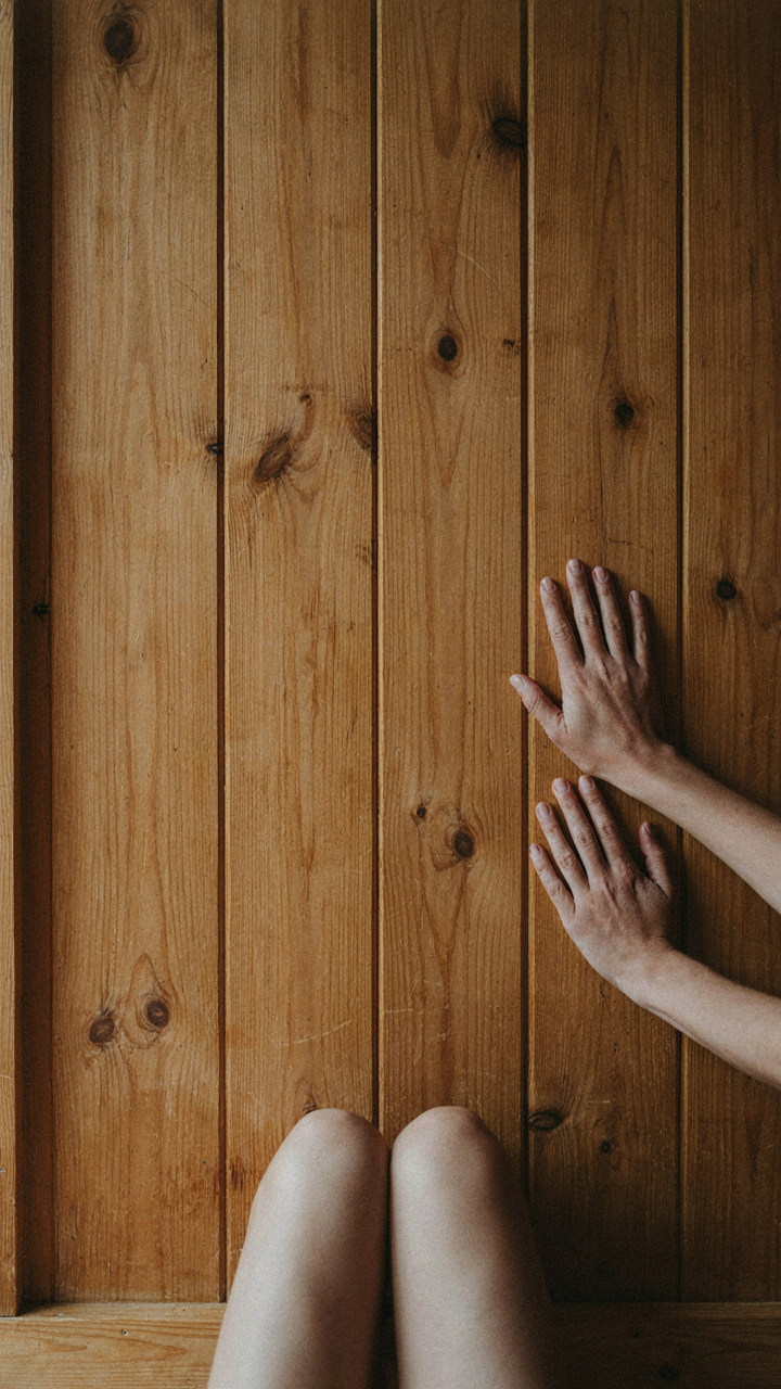 A hand gently touches an untreated pine wall in a nordic cabin.