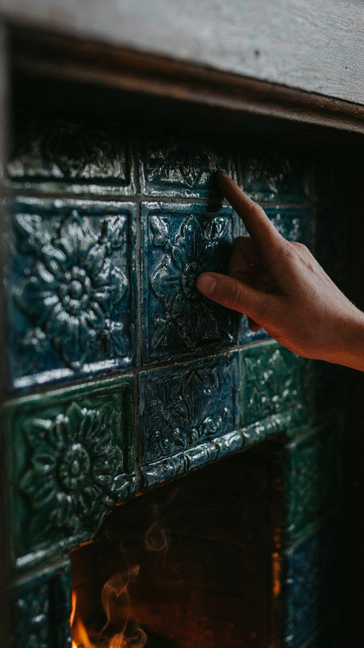 Close-up of thick glazed ceramic Victorian fireplace tiles radiating heat after a fire.