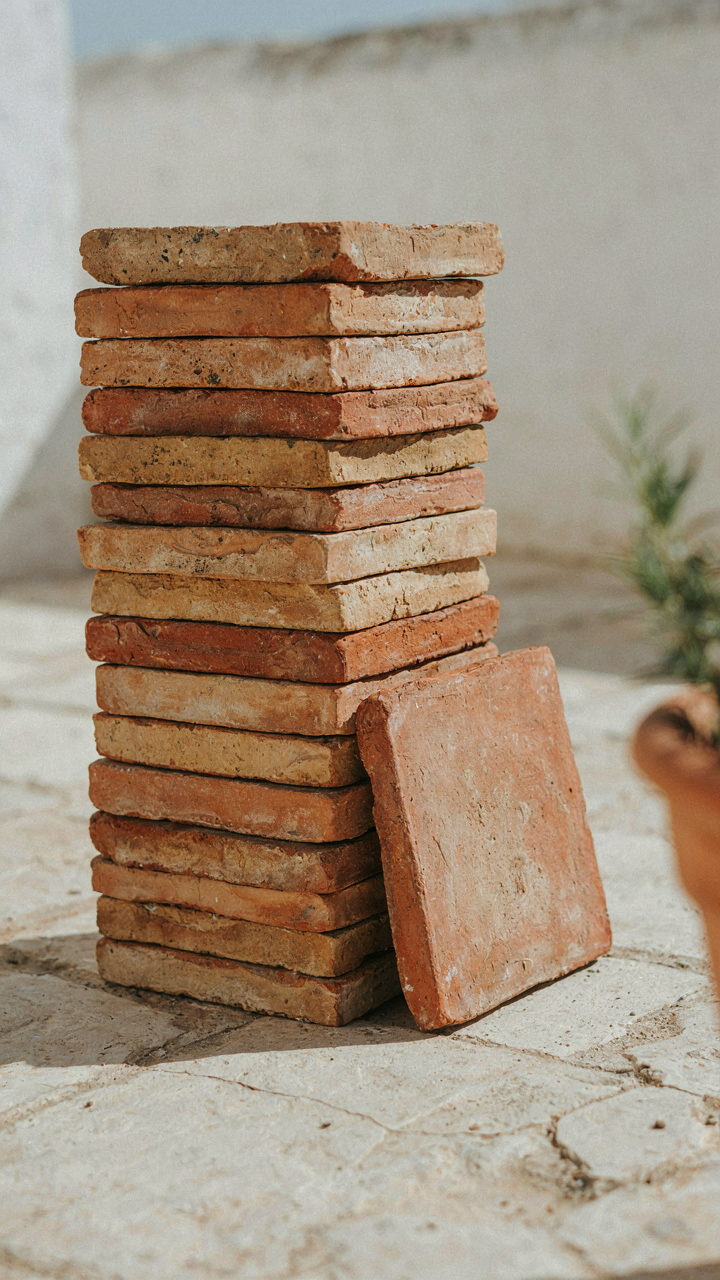 A stack of natural terracotta floor tiles with slight color variations.