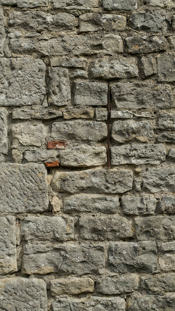 A cross-section of a thick, load-bearing stone wall with visible mortar joints.