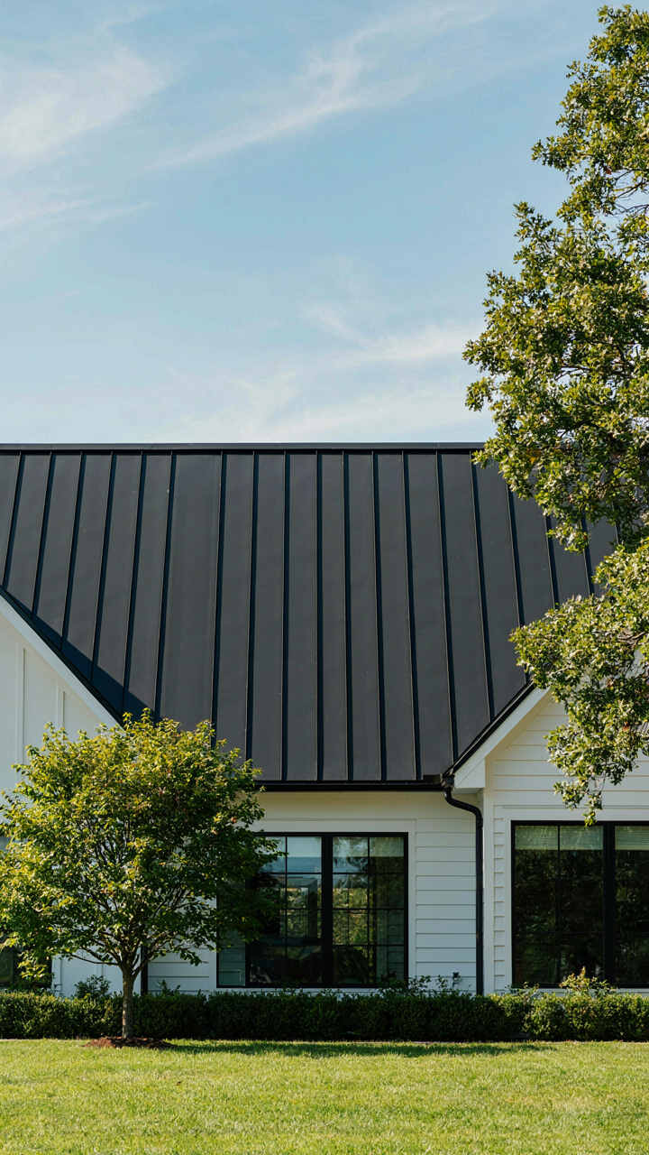 A modern cottage boasts a sleek, charcoal standing seam metal roof.