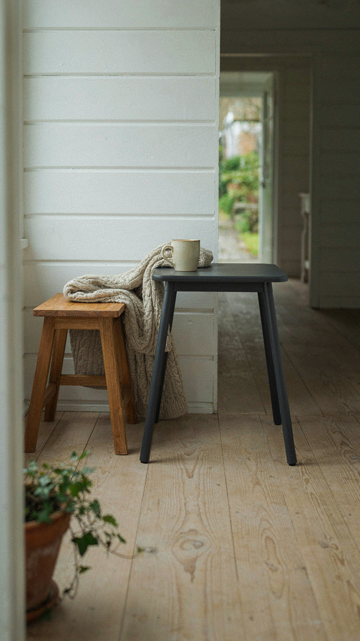 A minimalist tiny cottage porch with a side table and a stool.