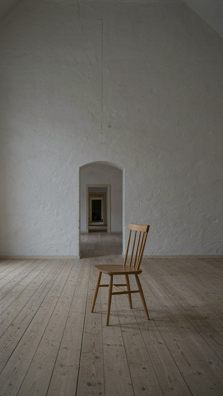 Clean, minimalist scandinavian barn house interior with a white wall and wooden chair.
