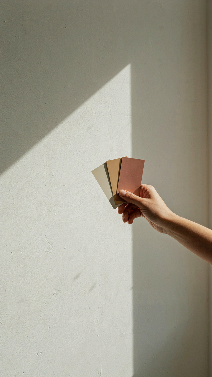 Three paint swatches held against a wall showing varying light conditions.