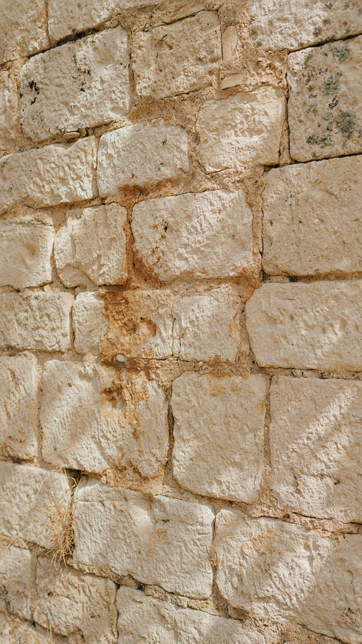 A close up of a weathered limestone wall showing subtle color variations and grout.