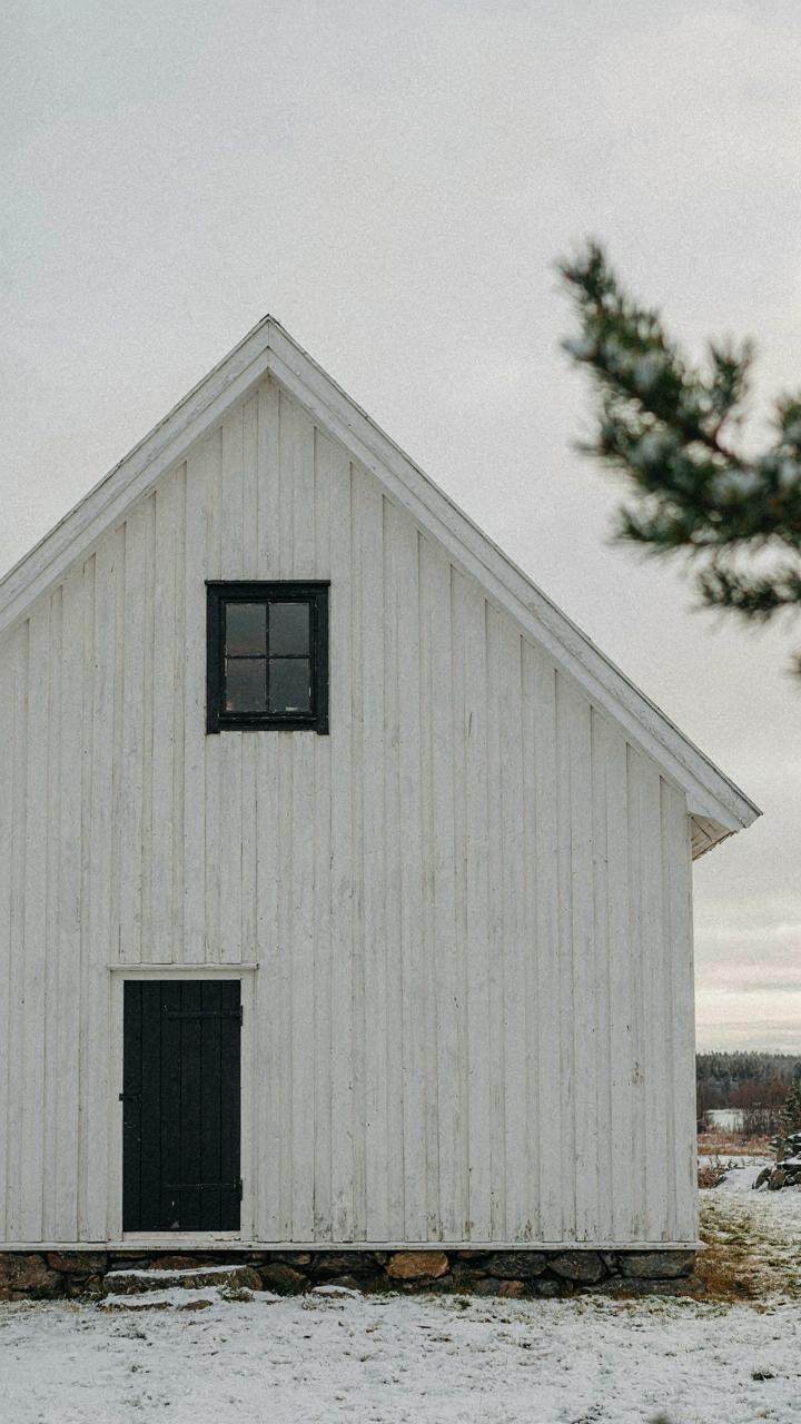 Thick, white-painted gable end of a nordic cabin exterior with soft light.