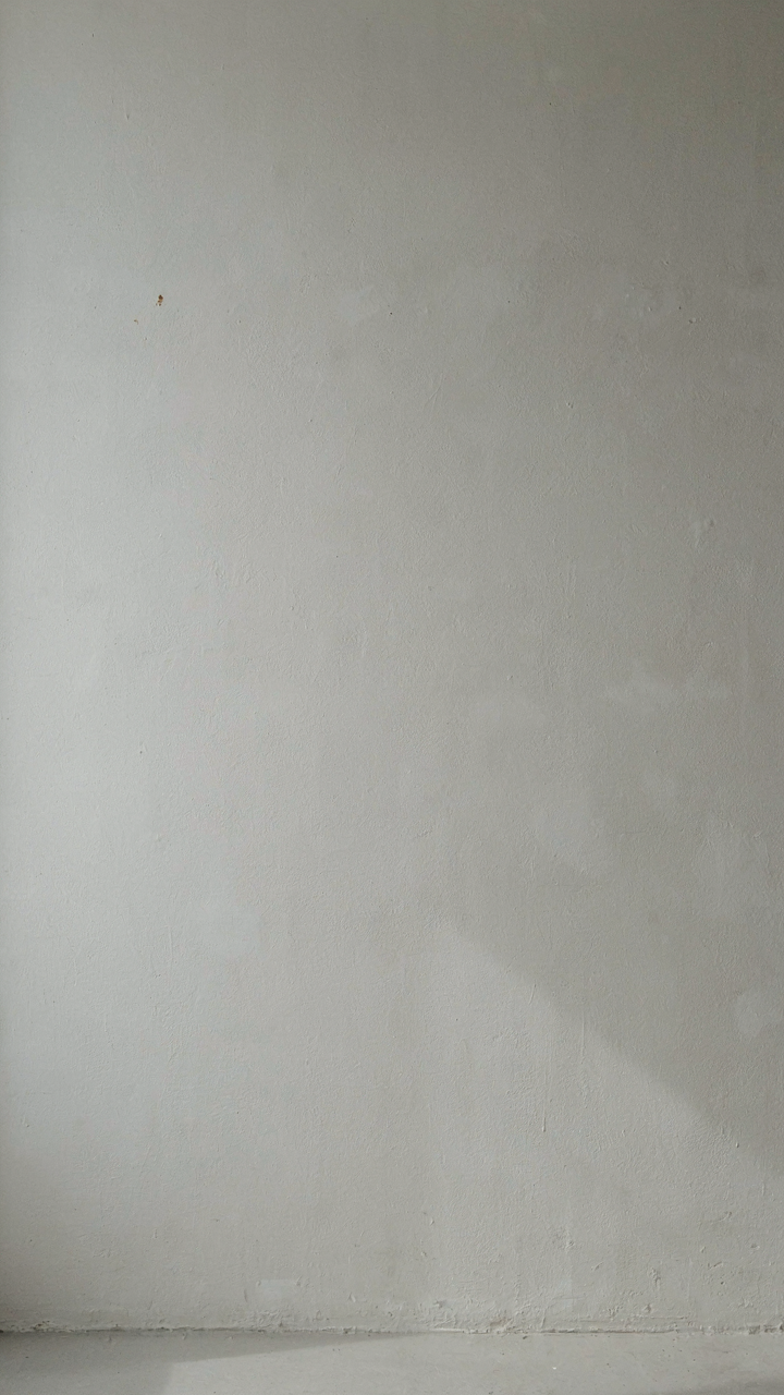 A matte off-white wall reflecting and diffusing light softly in a room.