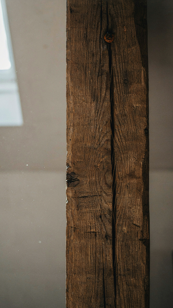 A close up of an authentic weathered hand-hewn beam in a simple room.