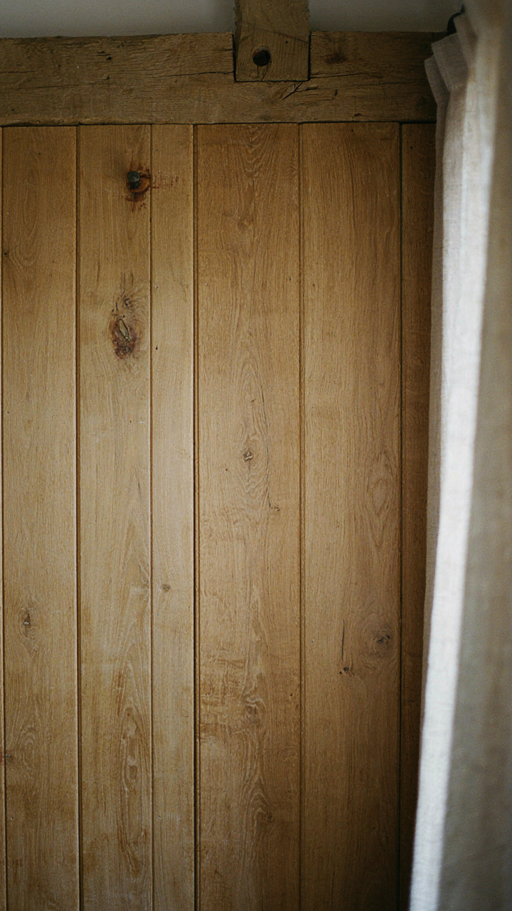 A close-up of original wooden wall paneling in a cottage guest bedroom.