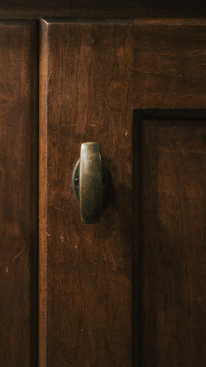 A brass cabinet handle shows a dark, aged patina.