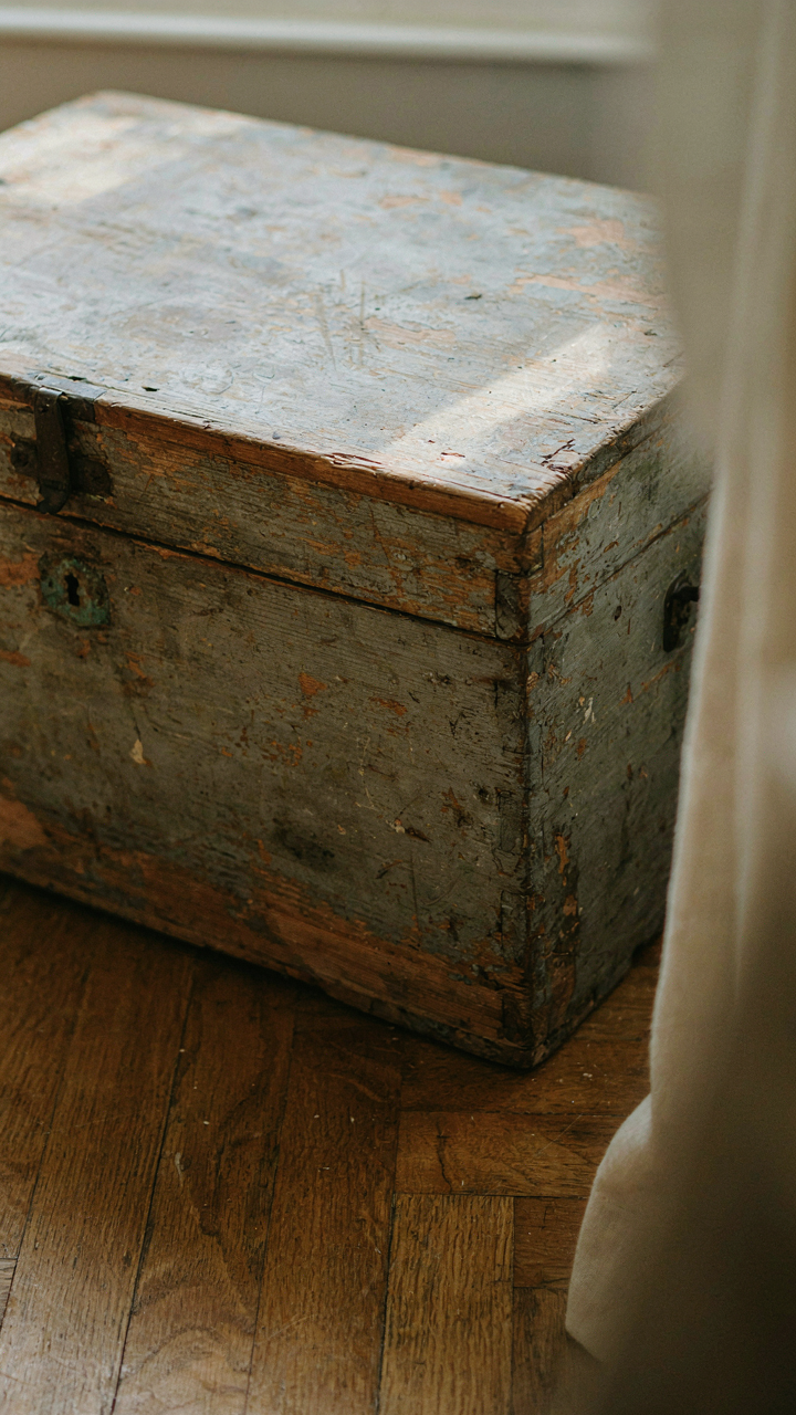 A close-up of an antique wooden chest with clear, uneven wear.