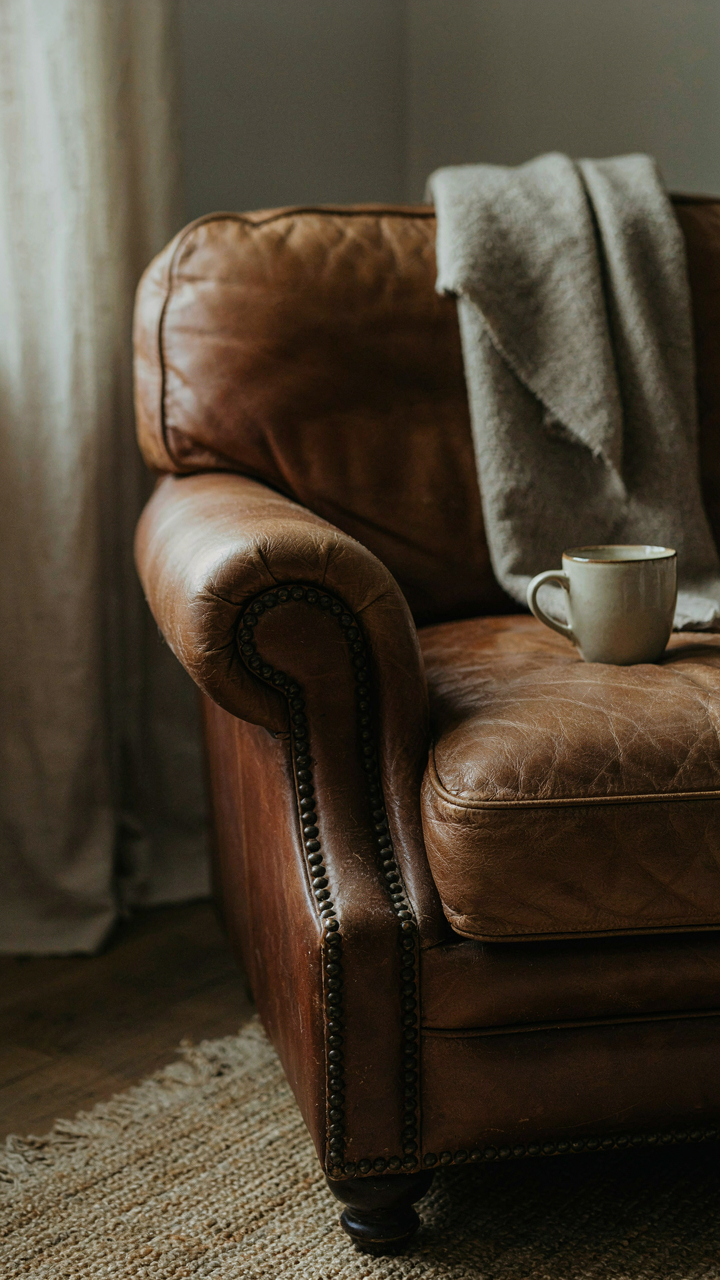 A close-up of a leather armchair with visible wear and tear.