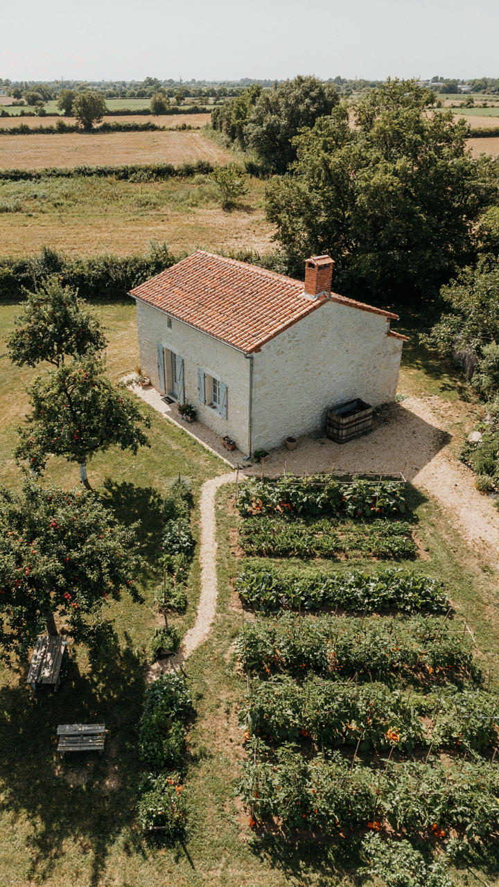 An aerial view of a European cottage with a garden and water barrel.