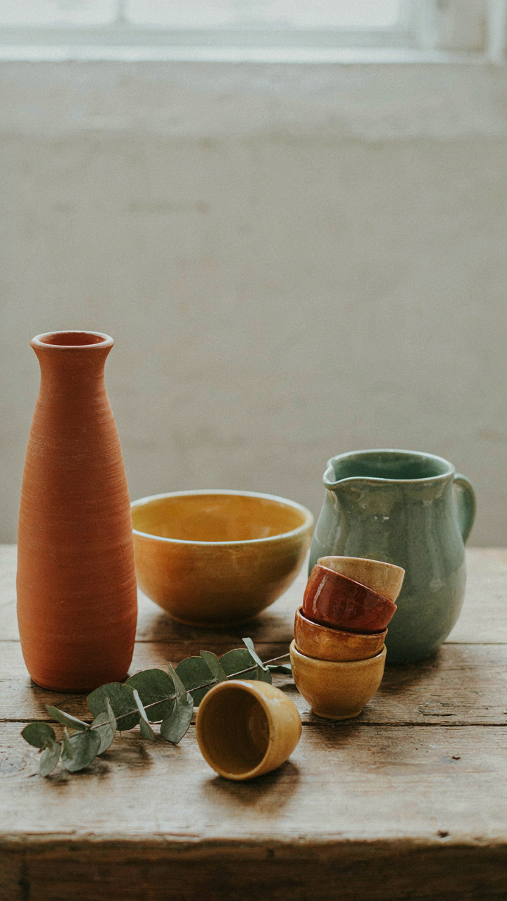 Pottery in earthy tones on a rustic wooden shelf.