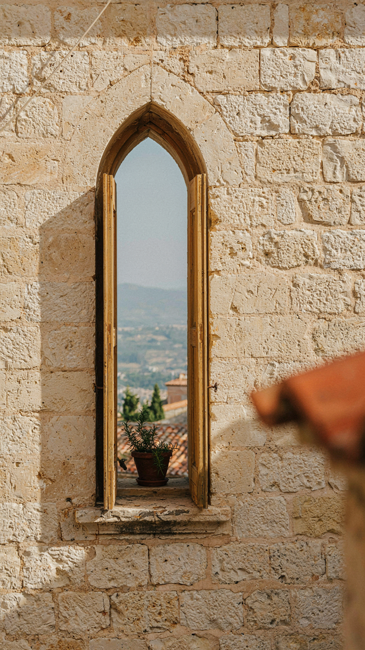 An open window in a thick, old stone wall, highlighting its simple design.