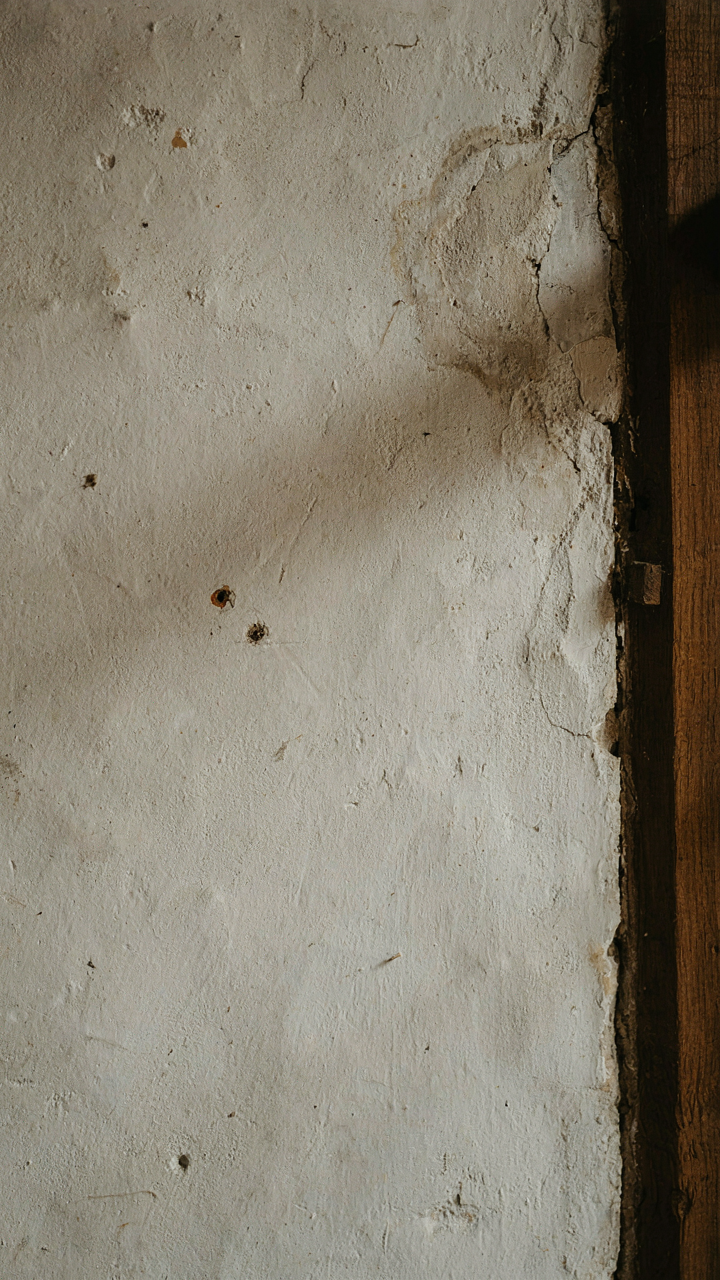 A close-up of a weathered lime plaster wall in an old cottage bedroom.